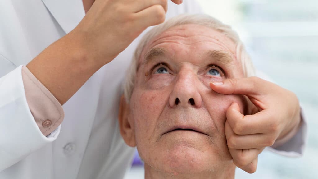 Oftalmologista examinando os olhos de um paciente idoso para avaliar sintomas de catarata