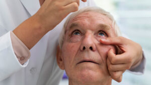 Oftalmologista examinando os olhos de um paciente idoso para avaliar sintomas de catarata